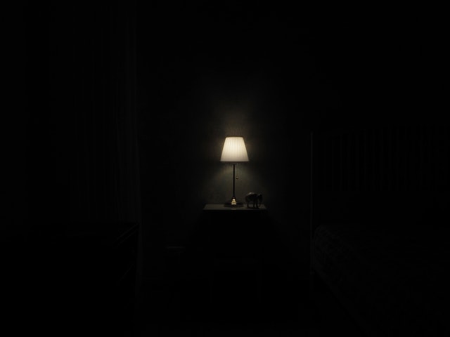 Zasvietená lampa na poličke v tmavej miestnosti.jpg