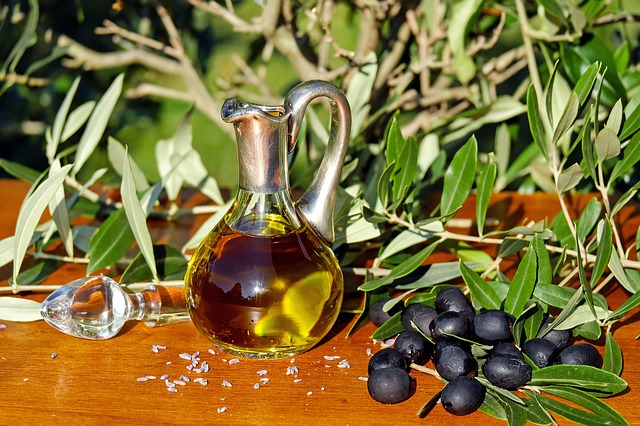 Olivový olej v sklenenej fľaši a čierne olivy.jpg